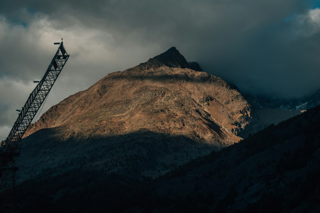 Construction crane working in an alpine mountain landscape