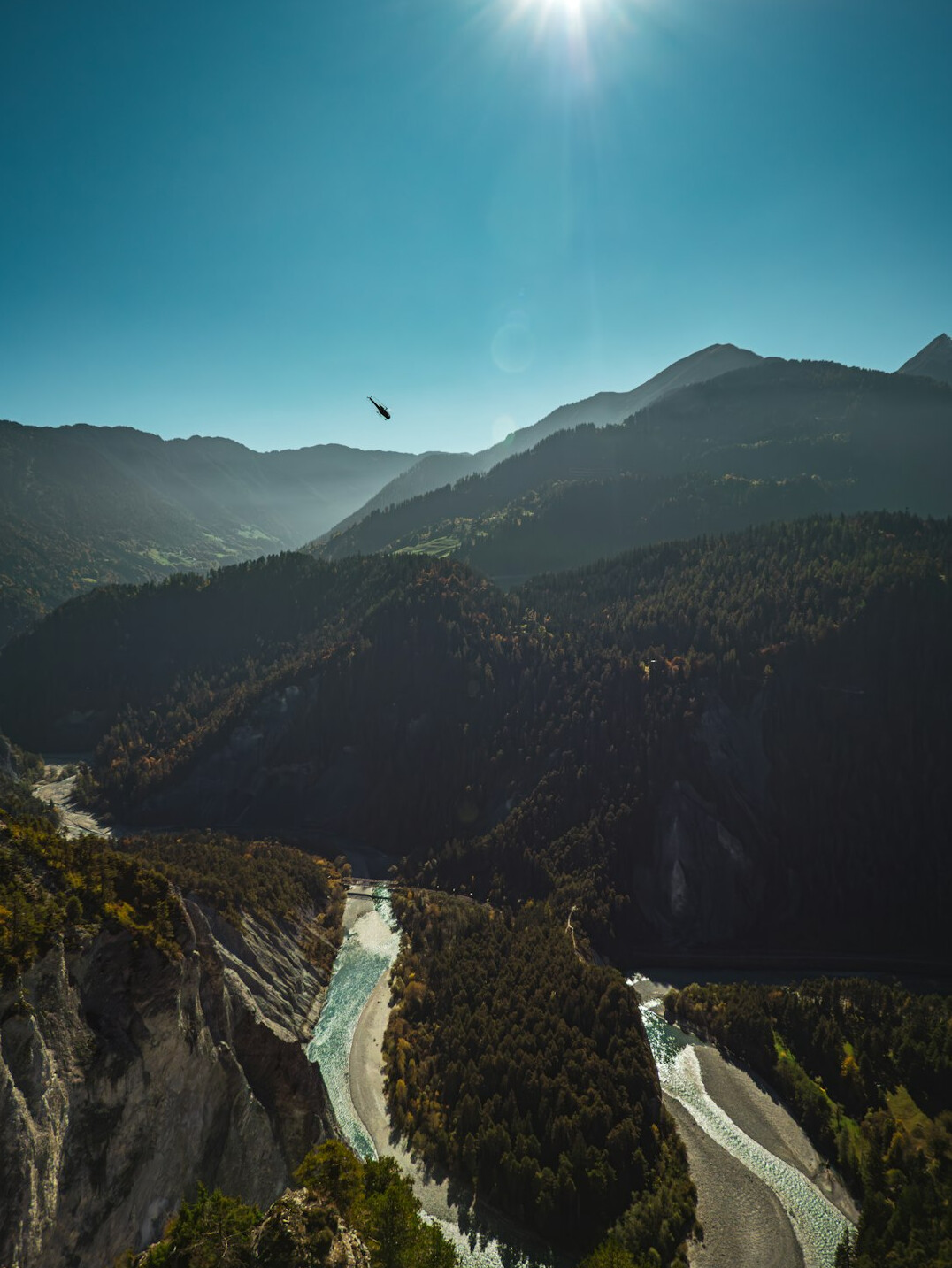 Aerial view of a Swiss alpine valley with a river and industrial facility